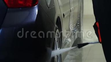 洗车。 洗车机清洗汽车。 一个洗车工人用水洗一辆车。 特写镜头。